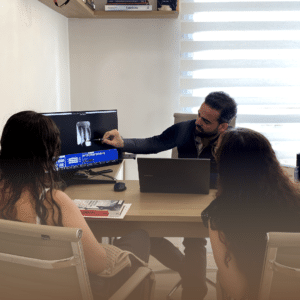 Dentista explicando o tratamento de canal para pacientes em um consultório odontológico, utilizando imagens digitais para um diagnóstico detalhado