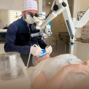 Dentista realizando tratamento de canal com microscópio operatório, garantindo precisão e segurança para o paciente.